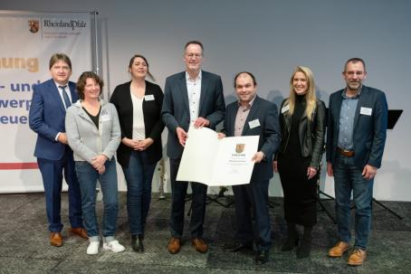 Innenminister Michael Ebling (Mitte) überreicht Ortsbürgermeister Tobias Rohrwick die Anerkennungsurkunde als Schwerpunktgemeinde der Dorferneuerung.
Mit dabei sind (v. l. n. r.) Landrat Heiko Sippel, Nicole Becker-Mutschler (Sachbearbeiterin Dorferneuerung Kreisverwaltung Alzey-Worms), Carolin Schreiber (Sachbearbeiterin Dorferneuerung VG Monsheim), Nicole Müller (stellv. Bauamtsleitung VG Monsheim) und VG-Bürgermeister Ralph Bothe.
Foto: Innenministerium RLP/Stephan Dinges